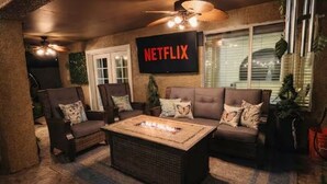 A cozy living room with a fireplace, comfortable seating, a TV mounted on the wall, and a ceiling fan. - The Cozy Inn (Phoenix)