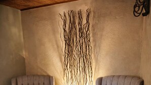 Two armchairs with 'Blessed' pillows, a small table with a plant, and a wall with a decorative branch arrangement. - The Cozy Inn (Phoenix)