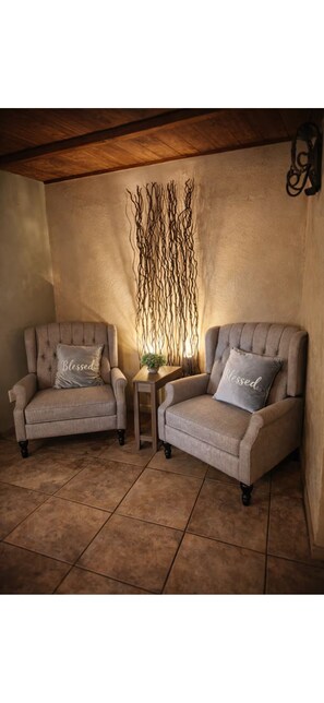 Two armchairs with 'Blessed' pillows, a small table with a plant, and a wall with a decorative branch arrangement. - The Cozy Inn (Phoenix)