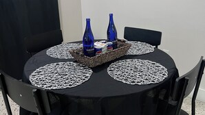 A round table with a black tablecloth, surrounded by four chairs, and two blue bottles on the table.