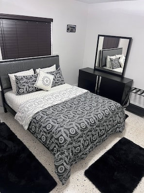 A bedroom with a bed, a dresser, a mirror, and a picture on the wall.