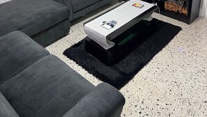 A living room with a grey sofa, a coffee table, a TV, and a floor lamp.