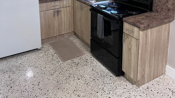 A kitchen with wooden cabinets, a white refrigerator, a microwave, a stove, and a ceiling fan.