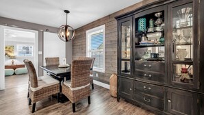 A dining area with a dark wood cabinet, wicker chairs, and a wooden table. - 1 Almost Heaven (Panama City Beach)