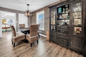 Un coin repas avec un buffet en bois foncé, des chaises en osier et une table en bois.