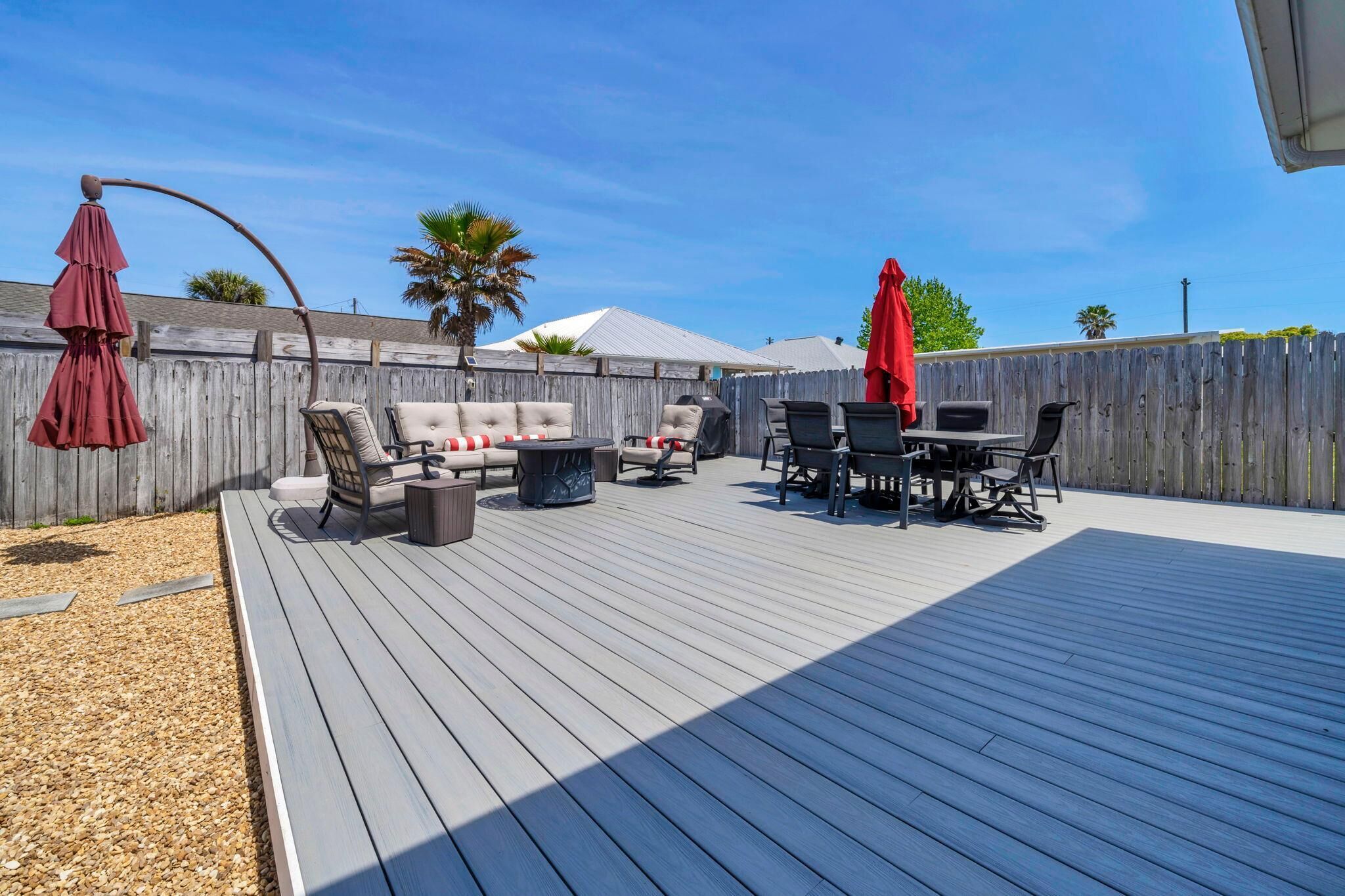 Una terraza de madera con mobiliario exterior, incluyendo un sofá, sillas y una mesa.