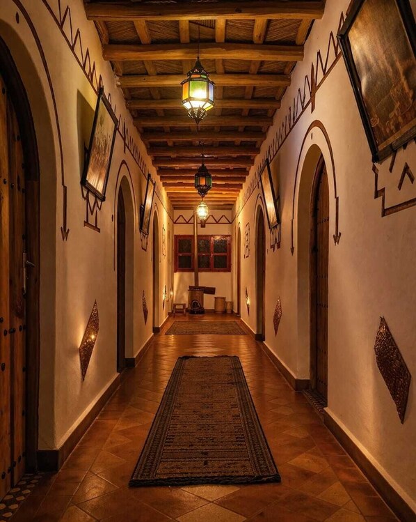 A hallway with wooden beams, arched doorways, and hanging lanterns.