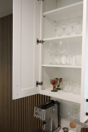 A kitchen with a coffee machine, a cabinet with wine glasses, and a fruit bowl. - North Park - Vibey Designer Home w/ King Beds Near Balboa Park, SD Zoo, & Cafés (San Diego)