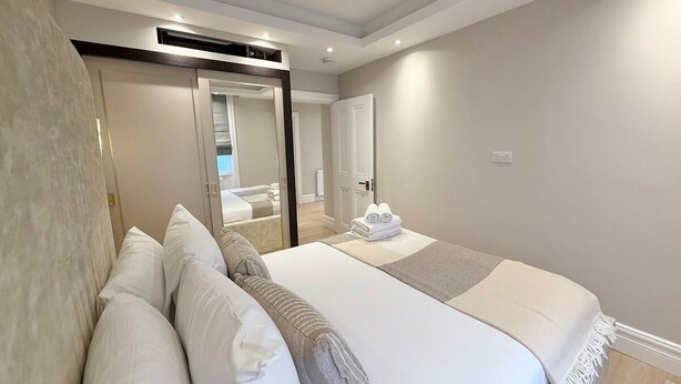 Een moderne slaapkamer met een groot bed, een spiegel en uitzicht op de badkamer.