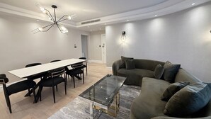 Een moderne woonkamer met een eetgedeelte, een glazen salontafel, een bank en een kroonluchter.