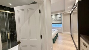 Een slaapkamer met een bed, een kledingkast en een douchecabine van glas.