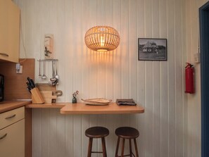 Una cocina con encimera de madera, dos taburetes, una lámpara colgante y un extintor.
