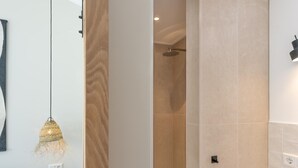 Ein modernes Badezimmer mit Dusche, einer Pendelleuchte und einer Holzbank.