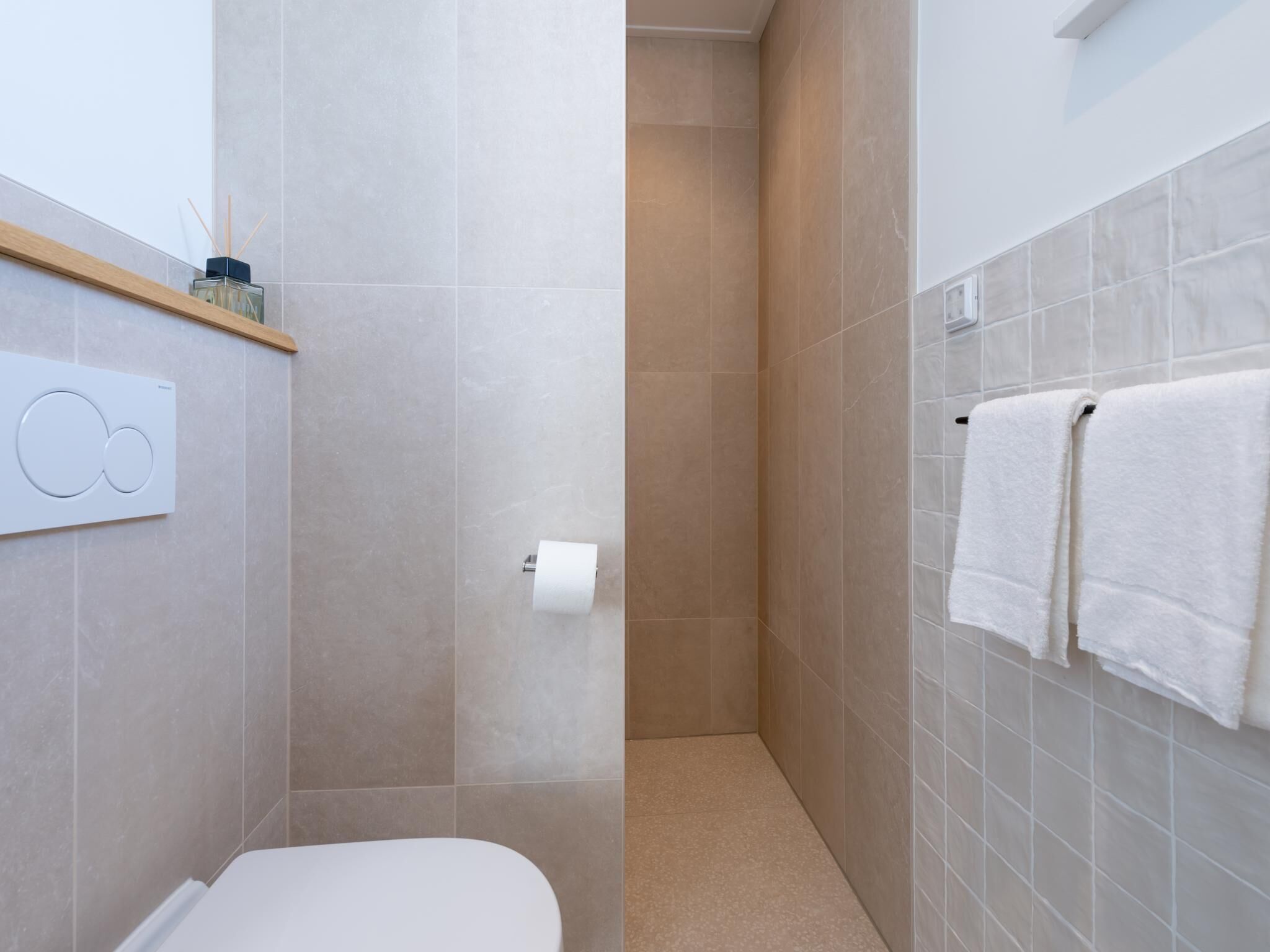 Ein modernes Badezimmer mit Toilette, Dusche und Handtuchhalter.