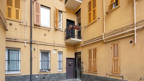 Ein Innenhof mit Steinboden, einer Tür und mehreren Fenstern mit Fensterläden.