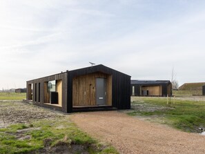 Un edifici modern amb façana de fusta, una porta i una petita finestra.