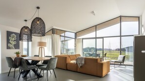 Un salon moderne avec une grande fenêtre, un canapé, une table à manger et un lustre.