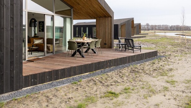 Un bâtiment moderne doté d’une terrasse en bois, de sièges extérieurs et offrant une vue sur le paysage environnant.