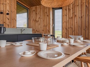 Ein Holzinterieur mit einem für vier Personen gedeckten Esstisch, einer Kaffeemaschine und einem Fenster mit Aussicht.