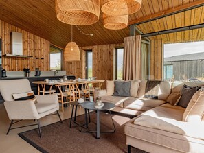 Ein modernes Interieur mit Holzbalkendecke, einem Essbereich, einer Couch und einem Couchtisch.