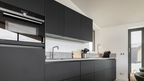 Cozinha moderna com armários escuros, pia de aço inoxidável e forno Siemens visível.