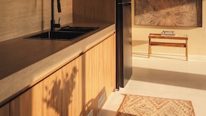 A modern kitchen with wooden cabinetry, a black faucet, and a large abstract painting on the wall. - Romantic 1BR Villa Canggu Pool & Sunset Balcony (Canggu)