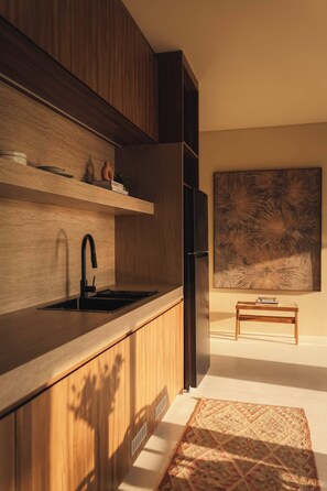 A modern kitchen with wooden cabinetry, a black faucet, and a large abstract painting on the wall. - Romantic 1BR Villa Canggu Pool & Sunset Balcony (Canggu)