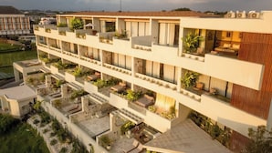 A multi-story hotel with balconies, outdoor seating, and a garden area. - Romantic 1BR Villa Canggu Pool & Sunset Balcony (Canggu)