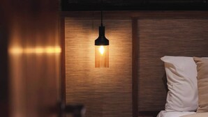 A bedroom with a wooden headboard, a bedside table, and a hanging light fixture. - Romantic 1BR Villa Canggu Pool & Sunset Balcony (Canggu)