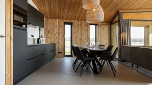 Eine moderne Küche mit Holzvertäfelung, einem Essbereich mit rundem Tisch und Stühlen sowie einem großen Fenster mit Blick.