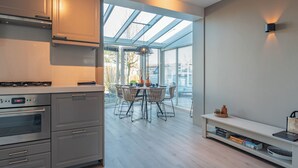 Eine moderne Küche mit integrierten Geräten, ein Essbereich mit Glasdach und ein Bücherregal.