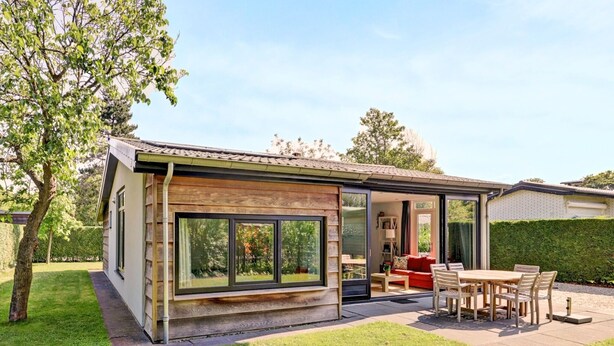 Ein modernes Haus mit Terrasse, Essbereich und einem roten Sofa.
