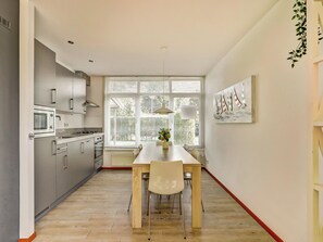 Una cocina moderna con comedor, ventanas amplias y vistas a la vegetación.