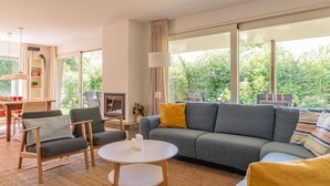 Ein modernes Wohnzimmer mit einem grauen Sofa, einem runden weißen Tisch und einem Bücherregal.