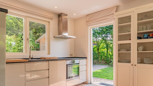 Eine moderne Küche mit großem Fenster, Einbauofen und Glaskabinett.