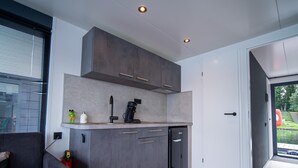Een moderne keuken met grijze kastjes, een koffieapparaat en een inbouwvaatwasser.