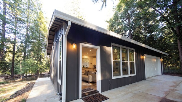 Ein modernes Haus mit Garage, überdachter Veranda und gepflegtem Rasen.