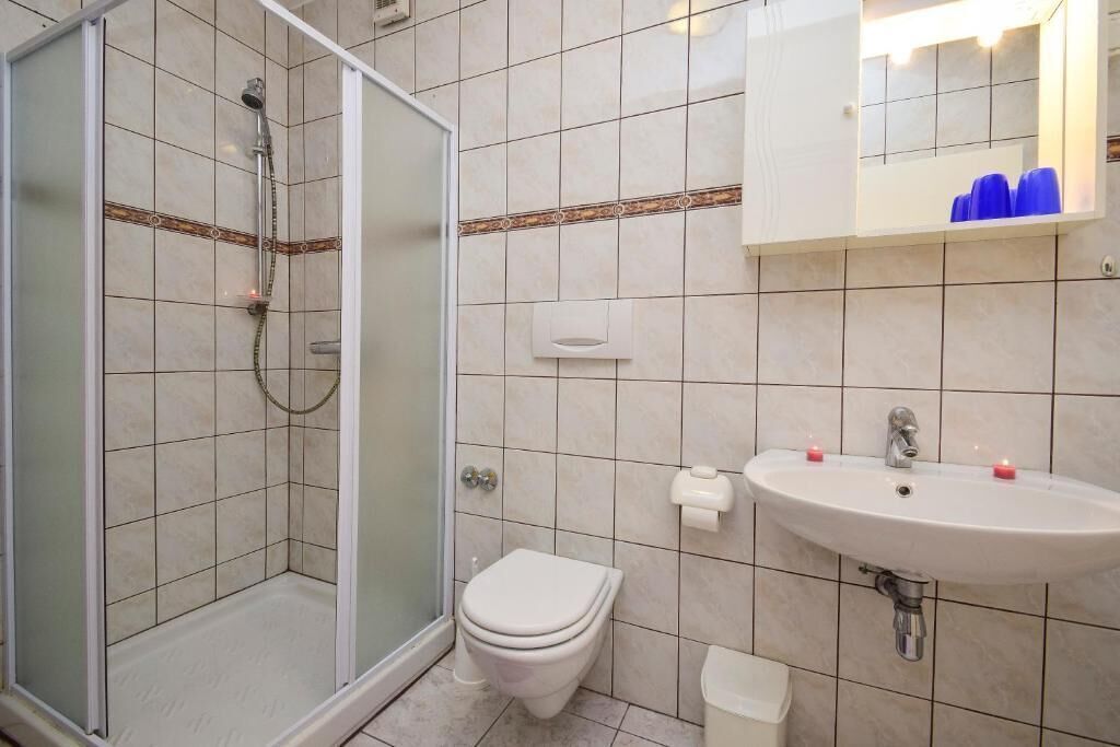A bathroom with a shower, toilet, sink, and a mirror above the sink.