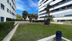 A courtyard with a grassy area, palm trees, and a trash bin. - 3 beds close to the marina and beach, walking distance to town center (Estepona)