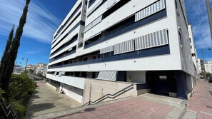 Een meerlaags gebouw met balkons, een trap en een heldere lucht.
