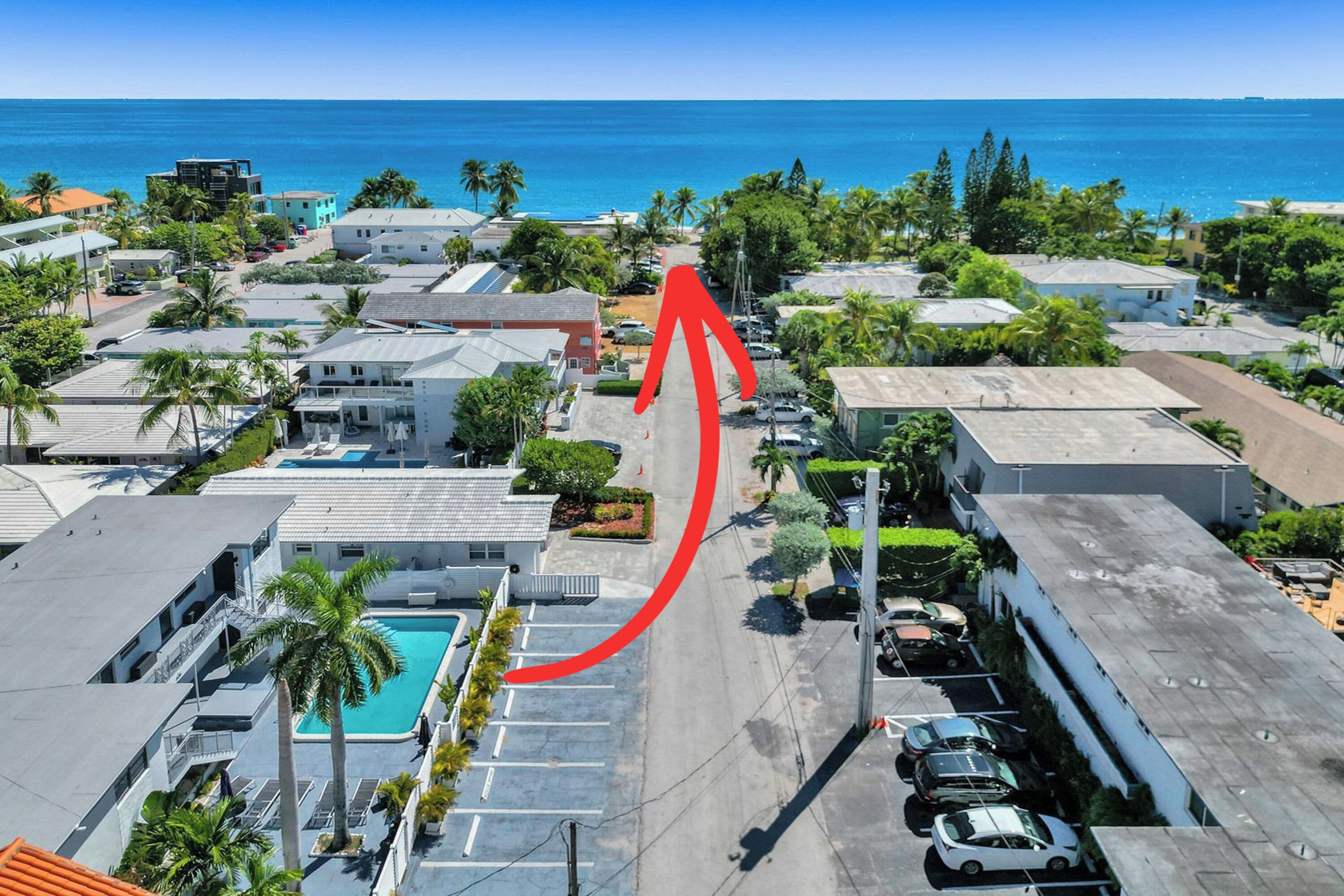 An aerial view of a coastal area with buildings, a swimming pool, and a view of the ocean.