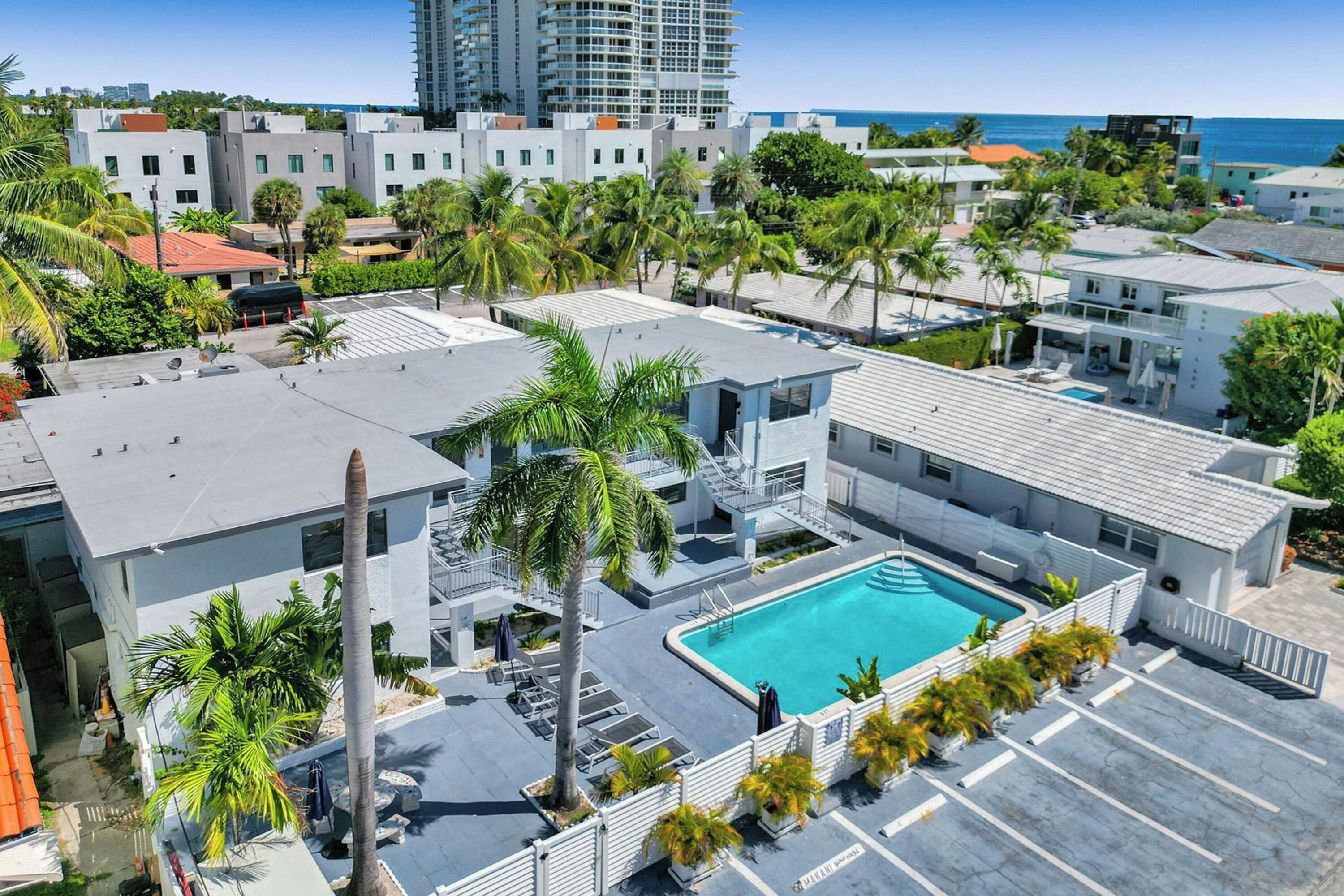 Un hotel moderno con piscina, palmeras y vista al océano.