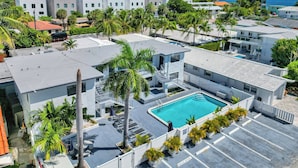Un hotel moderno con piscina, palmeras y vista al océano.