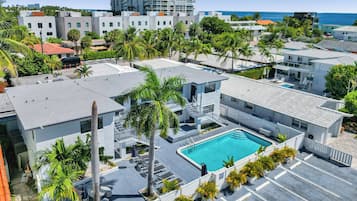 Un hotel moderno con piscina, palmeras y vista al océano.