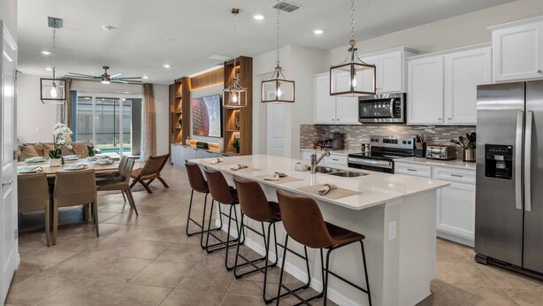 A modern kitchen with a central island, stainless steel appliances, and pendant lighting. - Themed 7BR Villa | Lion King · Frozen · Minions | Mario Game Room | Pool & Spa (Clermont)