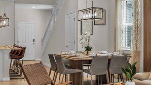 A modern dining area with a wooden table, grey chairs, and a hanging light fixture. - Themed 7BR Villa | Lion King · Frozen · Minions | Mario Game Room | Pool & Spa (Clermont)
