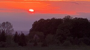 A sunset over a field with trees in the foreground. - Charming Charlevoix Camper Getaway Near Lake Michigan (Charlevoix)