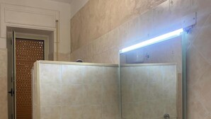 Een badkamer met toilet, wastafel, spiegel en douche.
