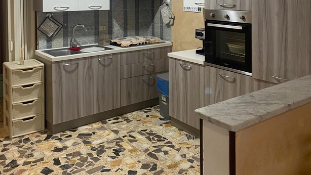 Een kleine keuken met een spoelbak, fornuis en kastjes.