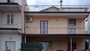 Een gebouw met twee verdiepingen, een balkon, een hek en een heldere lucht.